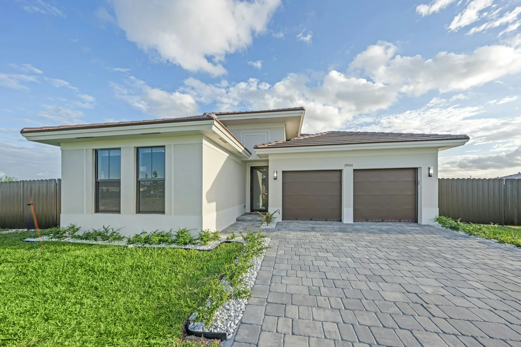 Single-story stucco house with a paver driveway and two-car garage
