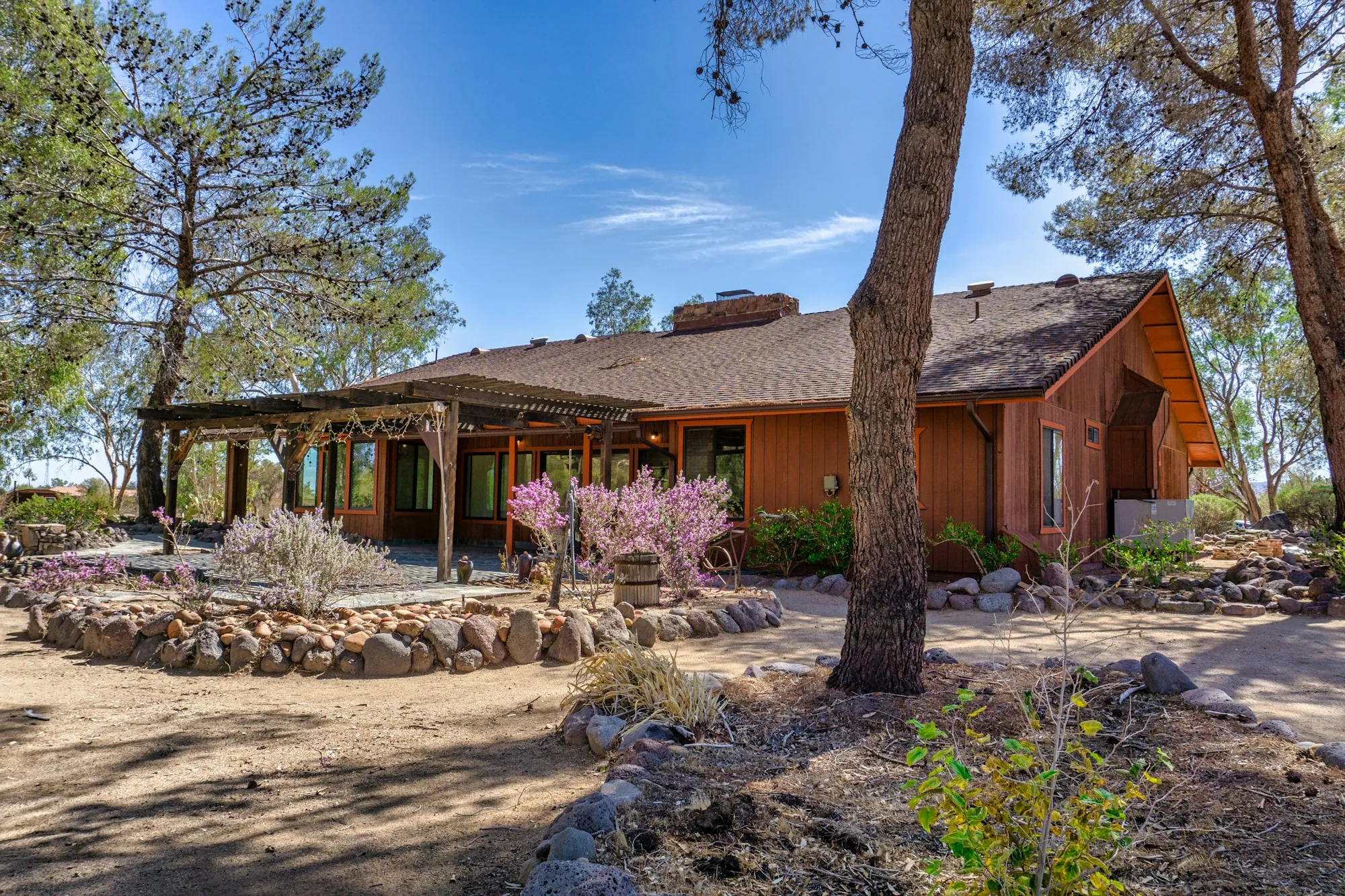 Single-story ranch home with native landscaping and tall pines